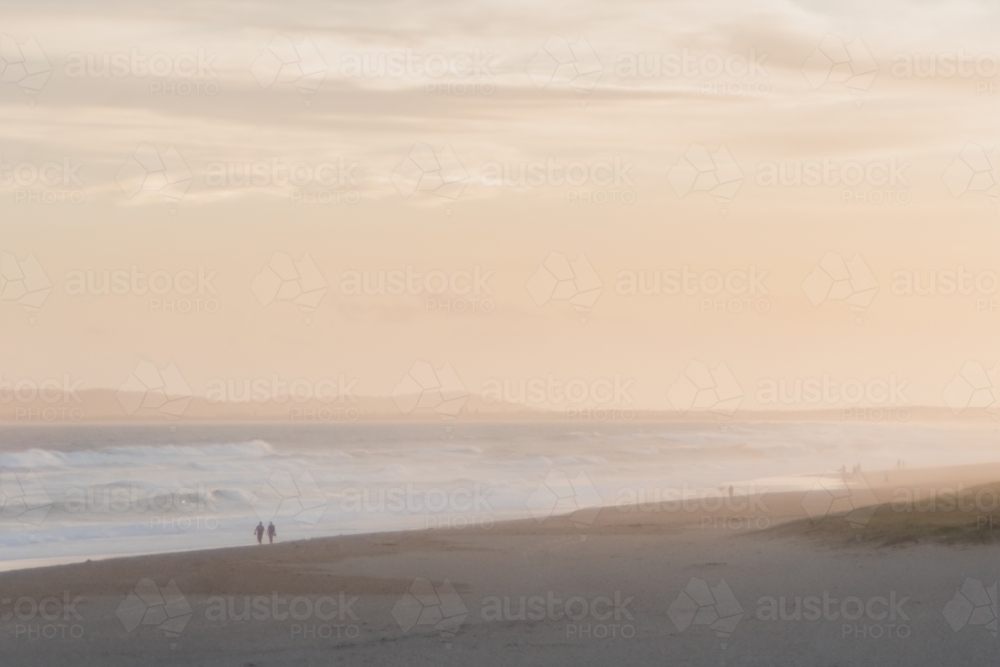 Couple taking a stroll on the beach at sunset - Australian Stock Image