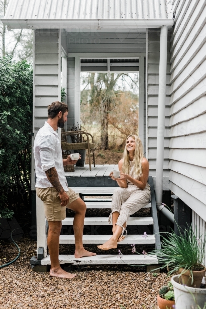 Couple talking on the steps of their front verandah : Austockphoto Couple talking on the steps of their front verandah - Australian Stock Image