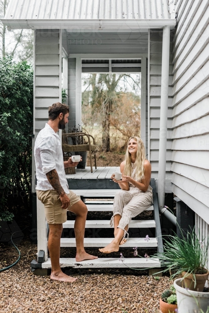 Couple talking on the steps of their front verandah - Australian Stock Image