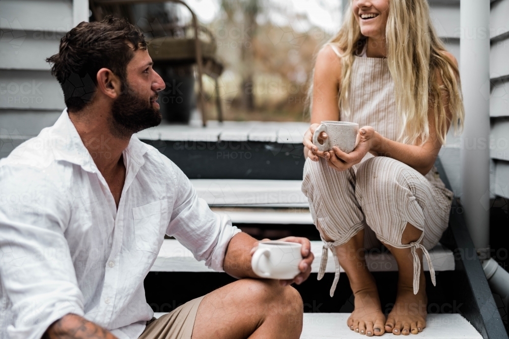 Couple talking on the steps of their front verandah - Australian Stock Image