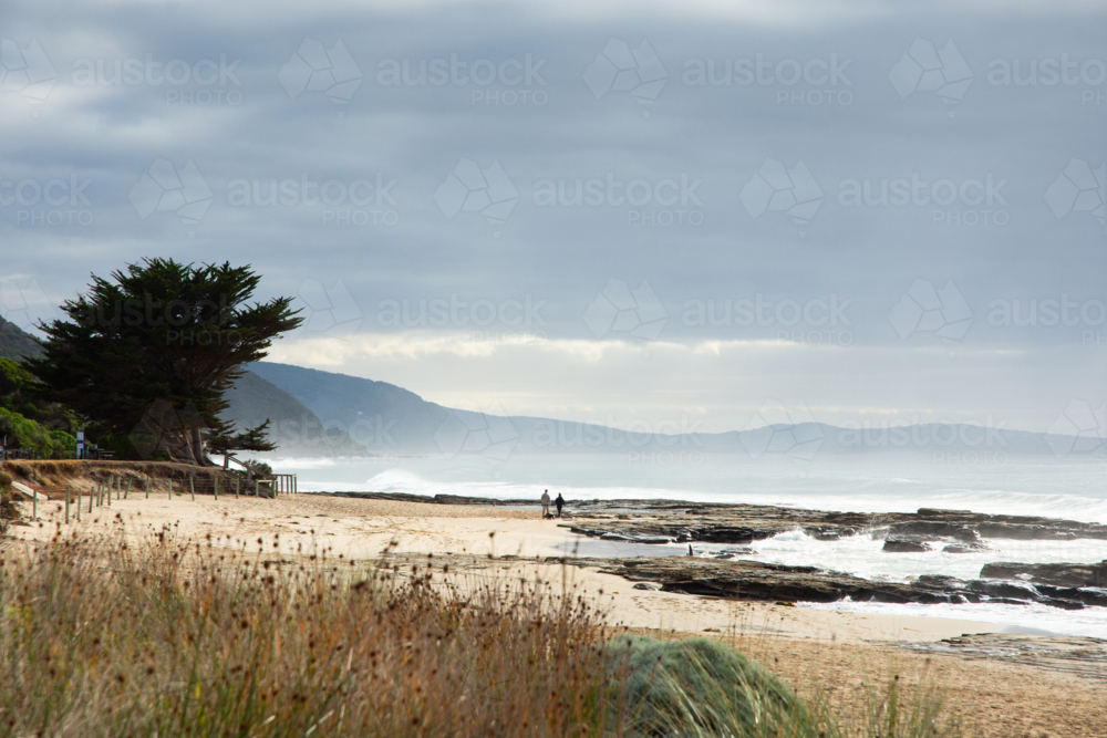 Couple walking on moody beach - Australian Stock Image