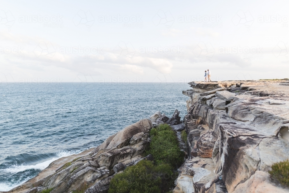 Couple walking toward edge of cliff overlooking ocean - Australian Stock Image