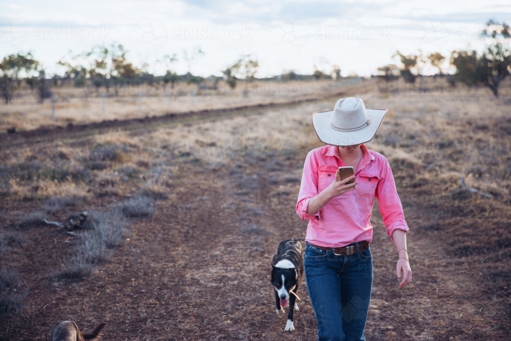 Cowgirl on smart phone with dog - Australian Stock Image