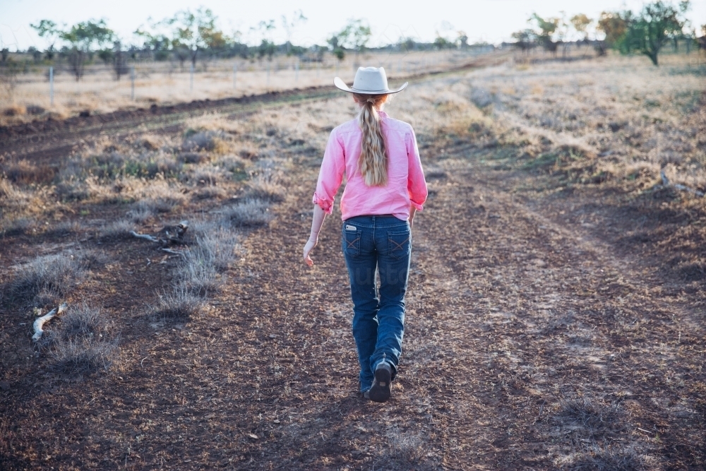 Cowgirl walking on dirt track - Australian Stock Image