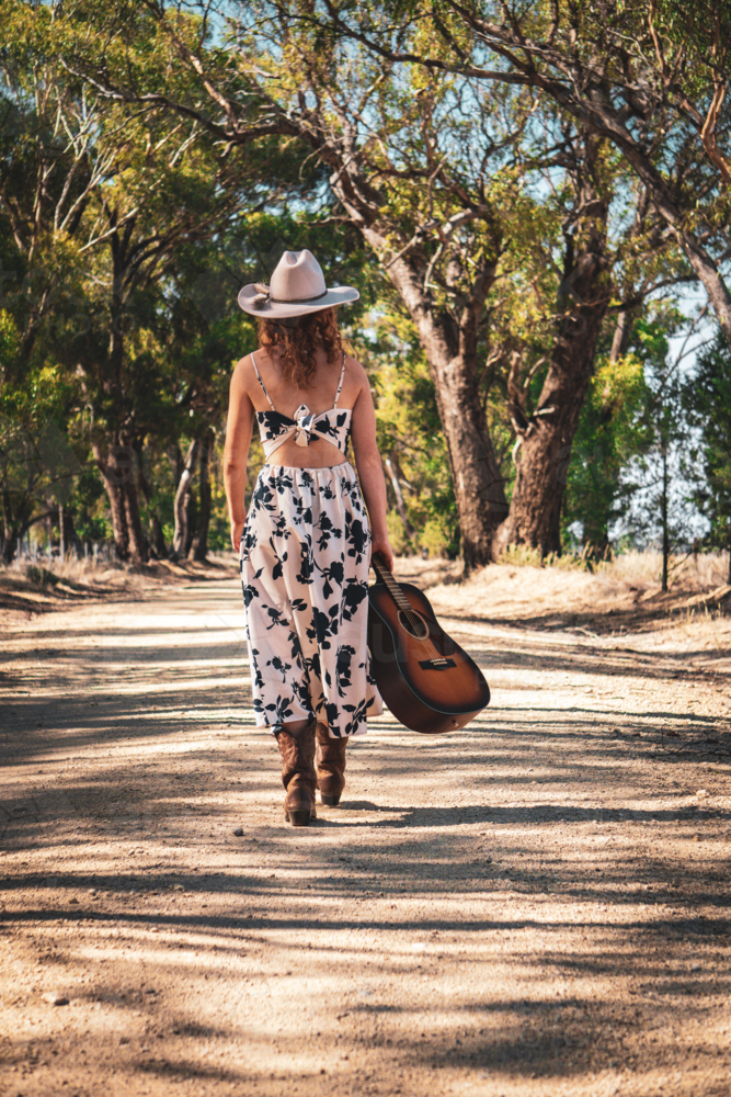 Cowgirl walking with a guitar - Australian Stock Image