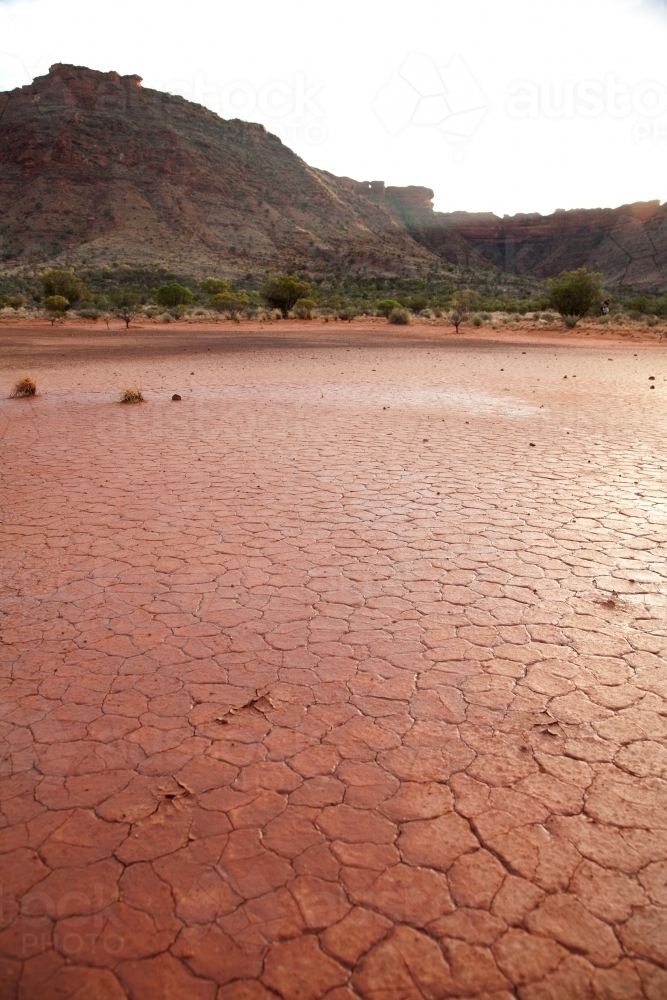Cracked red dry ground with mountains in background - Australian Stock Image