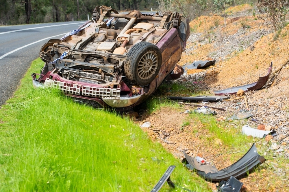 Image of Crashed car upside down on side of country road Austockphoto