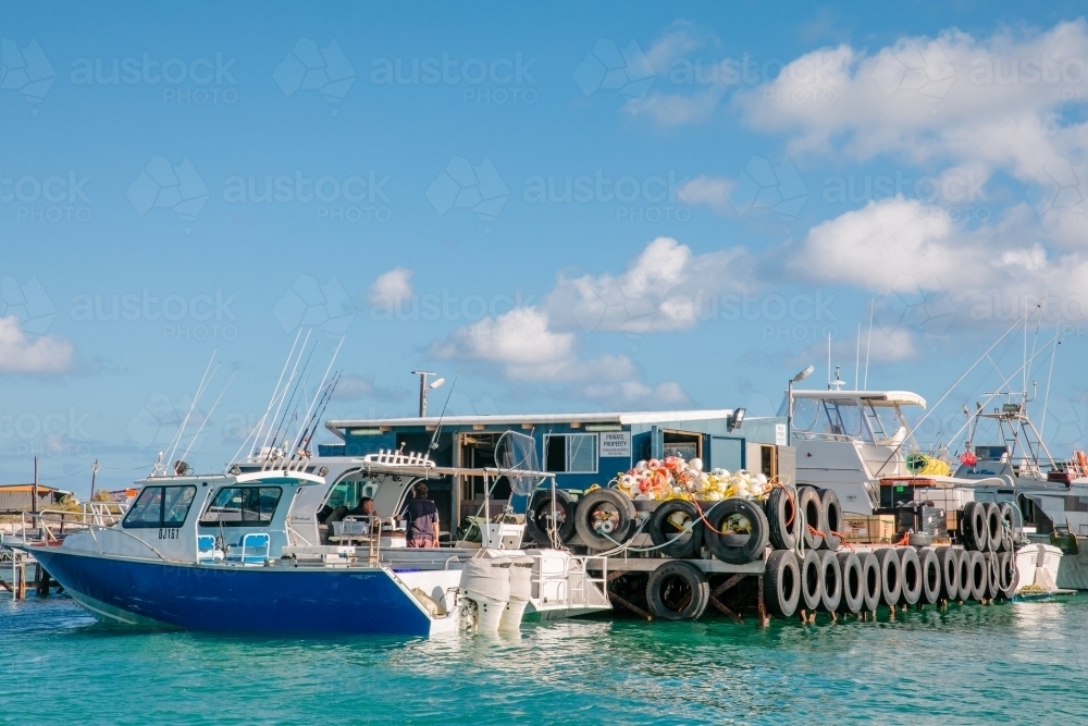Cray boats alongside an old wooden jetty with fishing shacks - Australian Stock Image