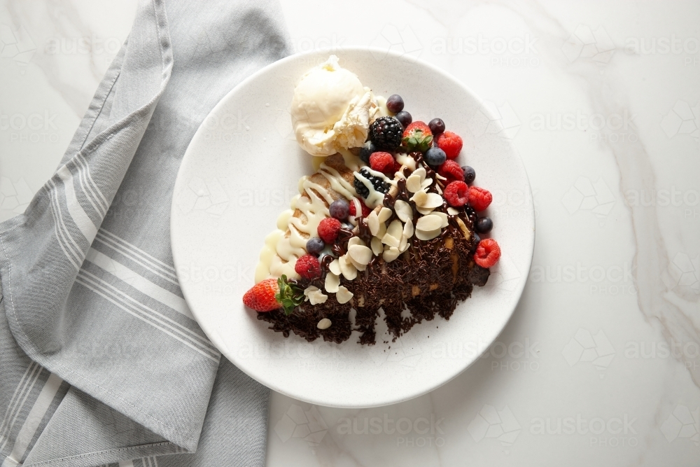 Cream cheese mixed berries crepe served in a white plate topped with sliced almonds. - Australian Stock Image