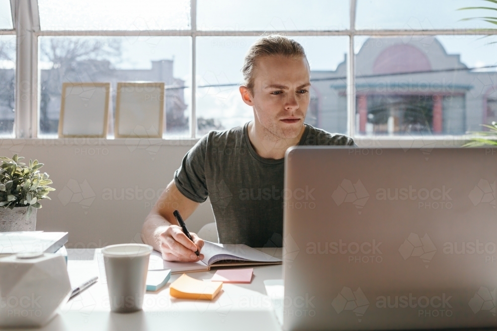 Creative employee at work with a laptop in the foreground - Australian Stock Image