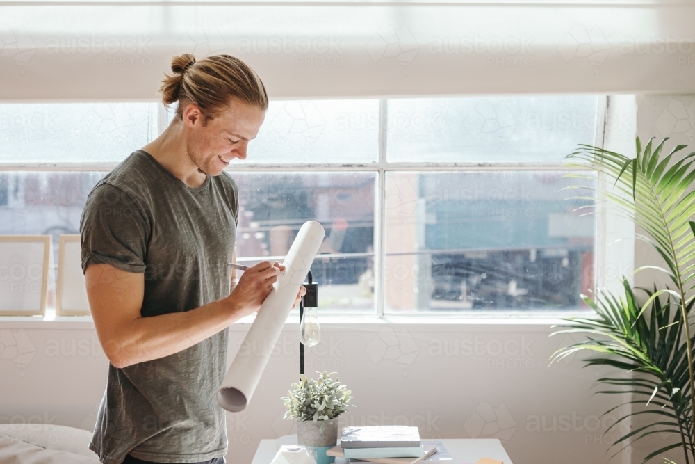Creative guy addressing a postal tube to despatch - Australian Stock Image