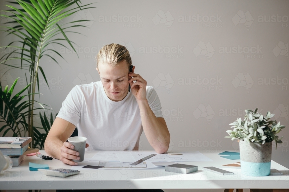 Creative guy drinking coffee at his desk - Australian Stock Image