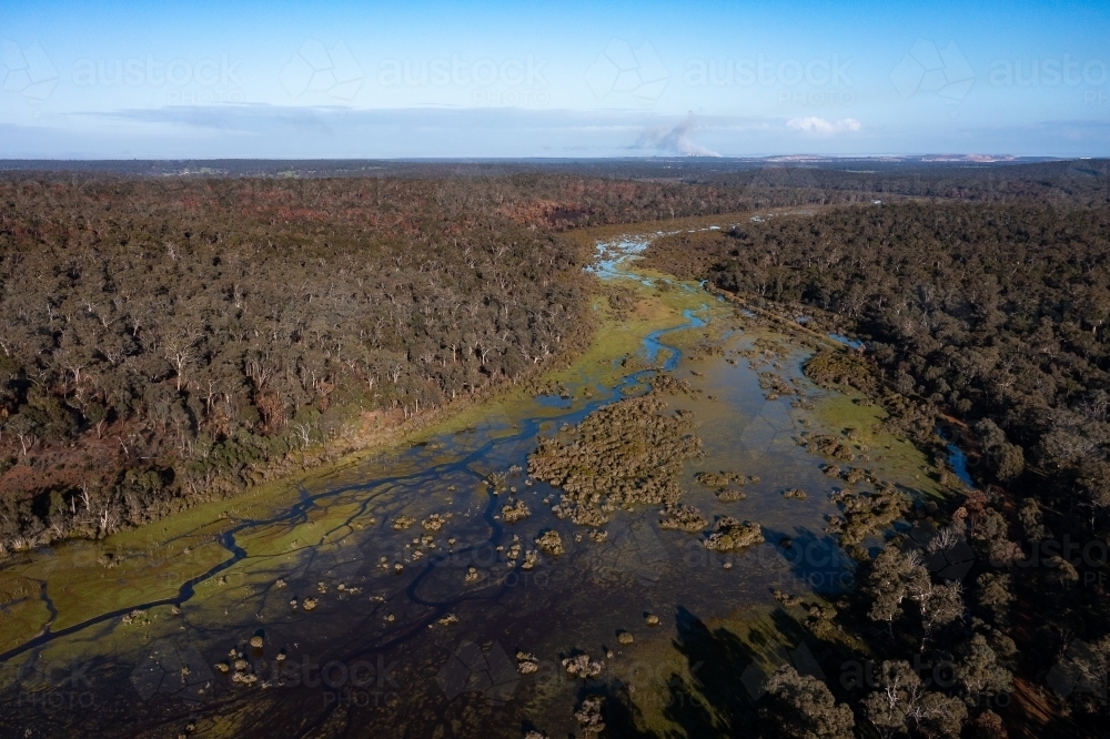 creek line running through bushland with distant mine on horizon - Australian Stock Image
