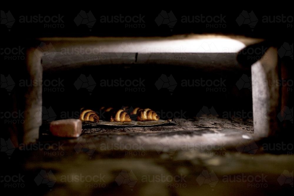 Croissants cooking in wood fired oven - Australian Stock Image