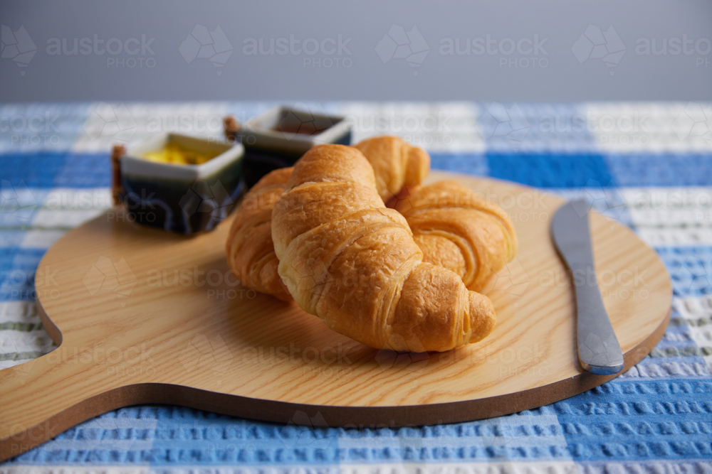 Croissants on serving board with blue tablecloth - Australian Stock Image