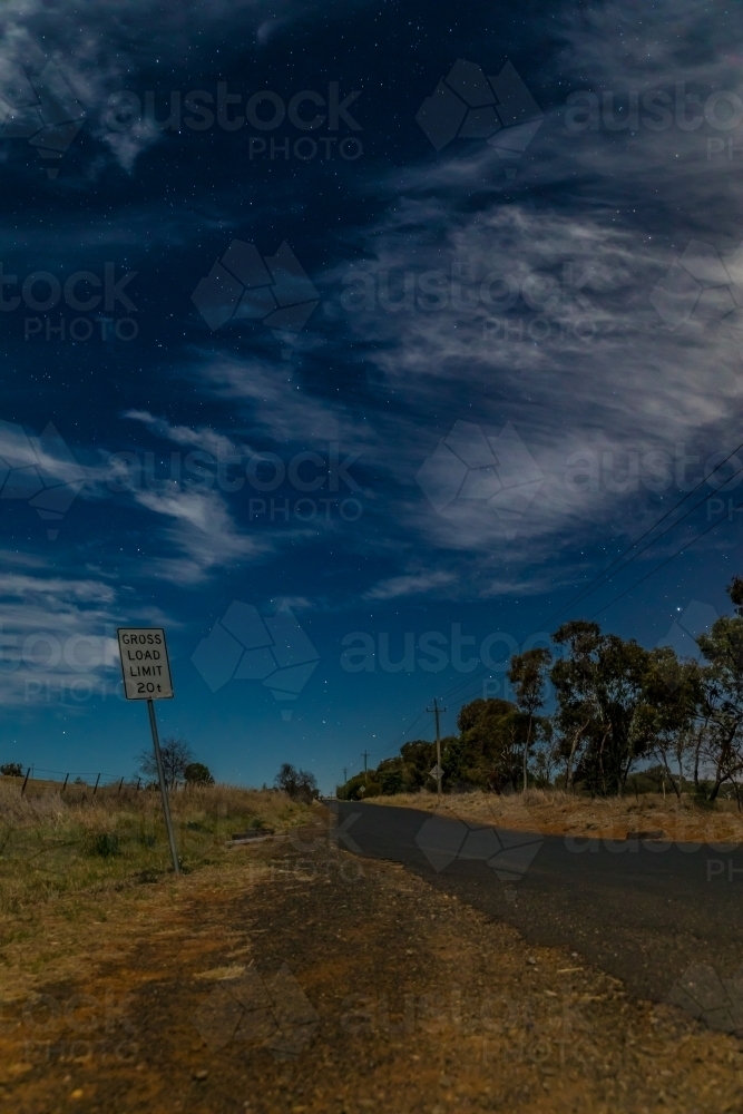 Crooked sign along a country road on a starry partly cloudy night - Australian Stock Image