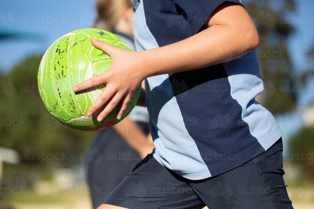 Cropped image of child running with ball - Australian Stock Image