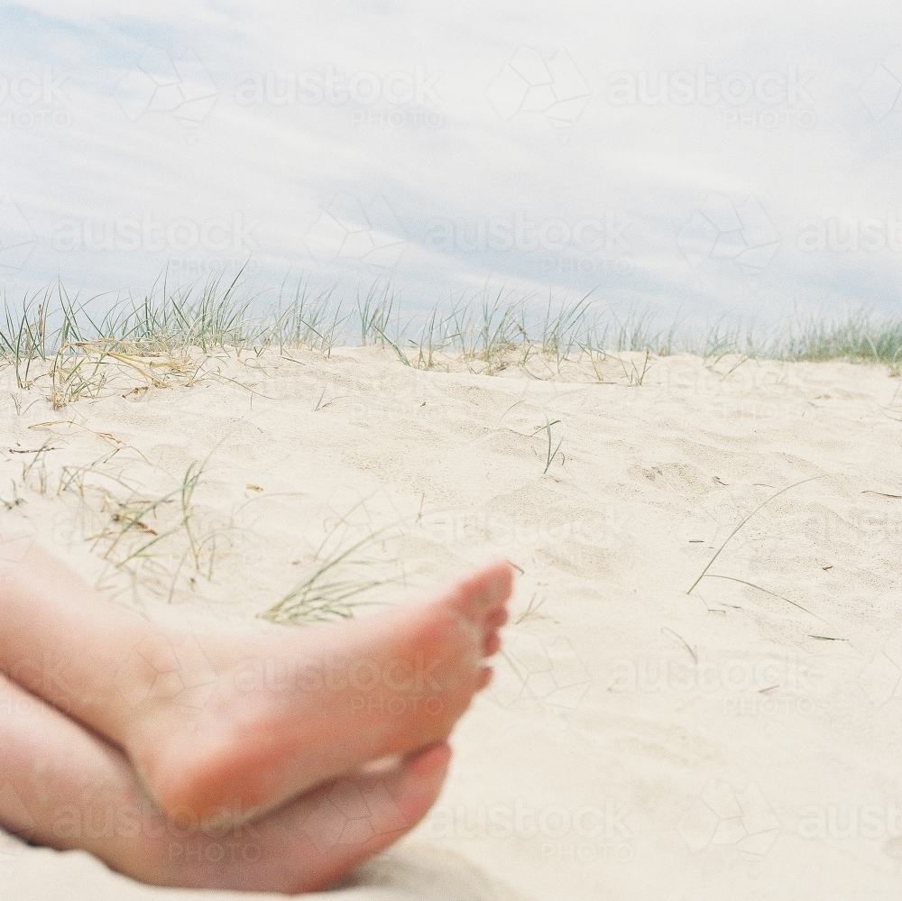 Cropped shot of bare feet on a sandy beach - Australian Stock Image
