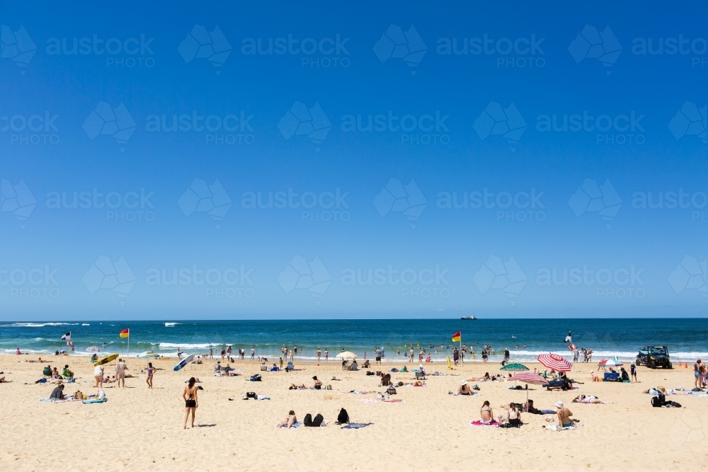 Crowd of people relaxing in sun and sand on Australian beach - Australian Stock Image