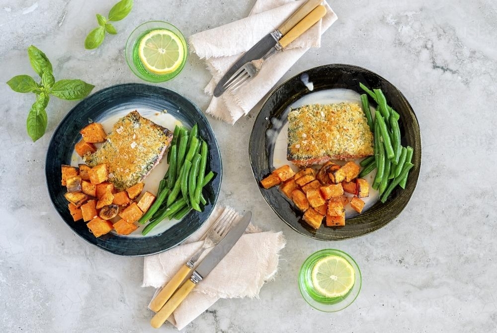 Crumbed salmon with green beans presented on table - Australian Stock Image
