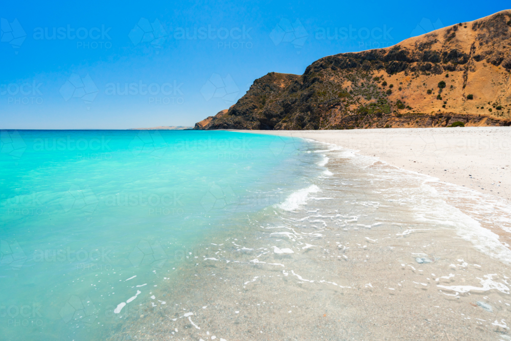 Crystal-clear turquoise water laps against a pristine white-sand beach - Australian Stock Image