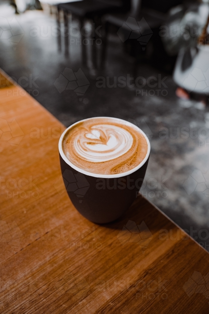 Cup of cafe coffee with latte art on a wooden table. - Australian Stock Image