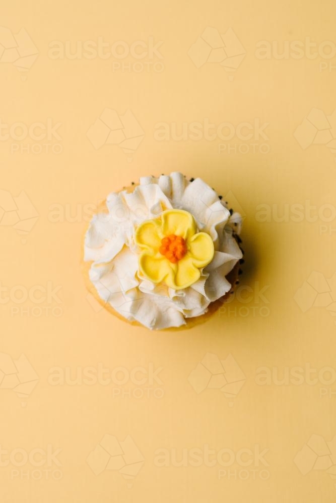 cupcake on yellow background with yellow flower - Australian Stock Image