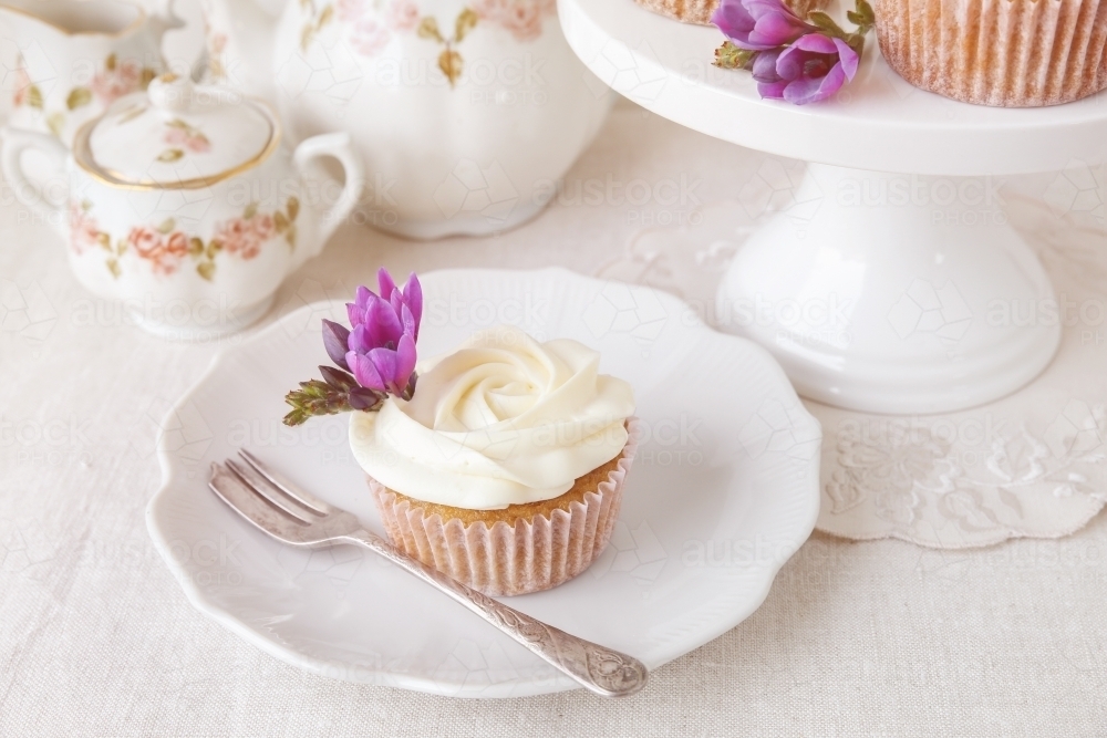 cupcakes with purple edible flowers for tea party - Australian Stock Image