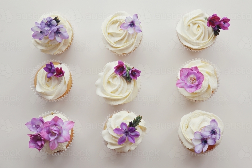 Cupcakes with purple edible flowers for tea party - Australian Stock Image