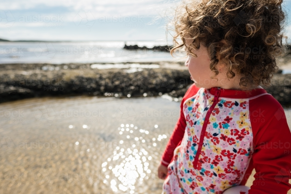 Curly hair toddler at beach - Australian Stock Image