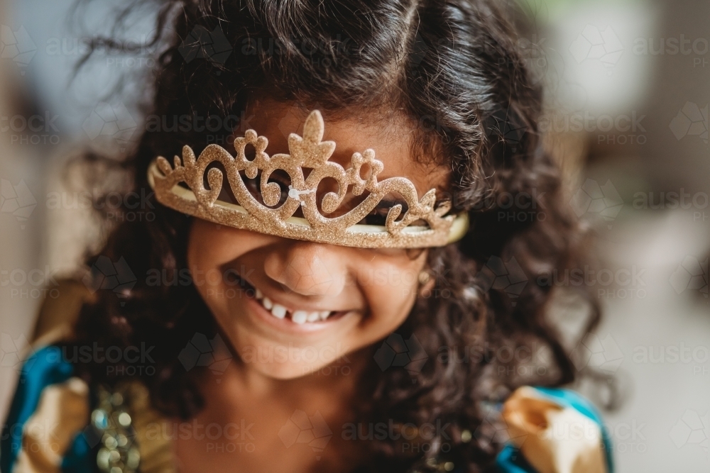 Curly haired girl smiling with the tiara on her face - Australian Stock Image