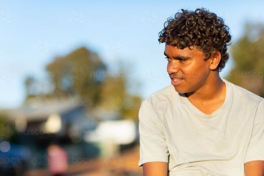 curly-haired teen boy looking away with blurry background - Australian Stock Image