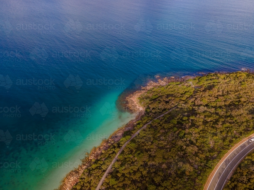 Curved road along coastline surrounded by bush scrub - Australian Stock Image