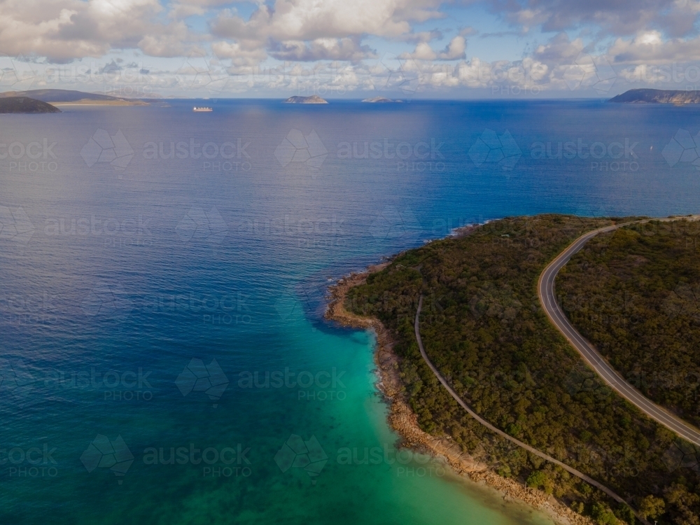 Curved road along coastline surrounded by bush scrub - Australian Stock Image
