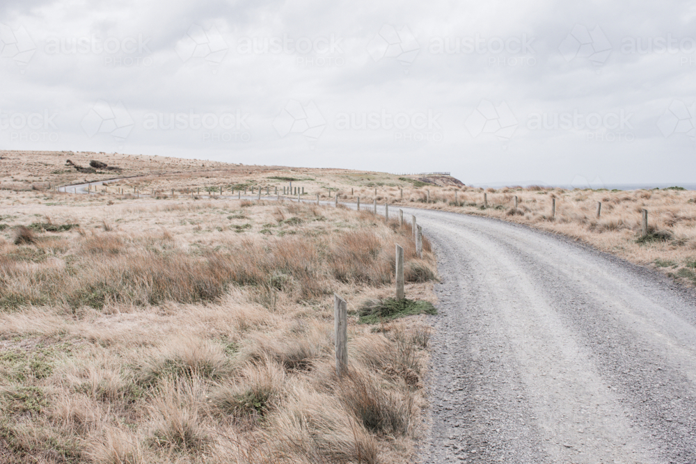 Curving, gravel track with posts and dry, summer grasses - Australian Stock Image