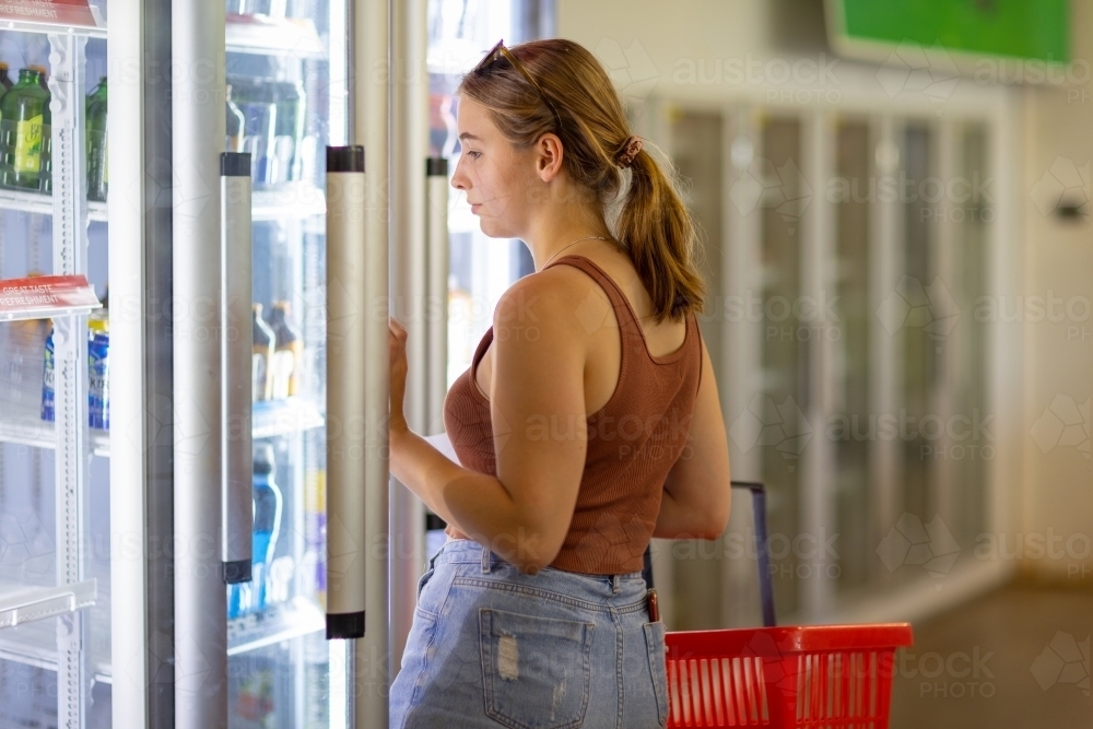 customer opening fridge door in small local supermarket - Australian Stock Image