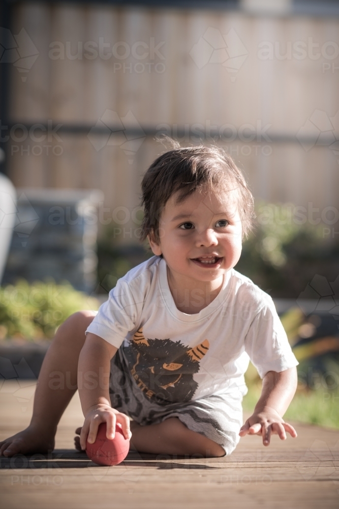 Cute 1 year old boy takes his first steps outside in his suburban backyard - Australian Stock Image