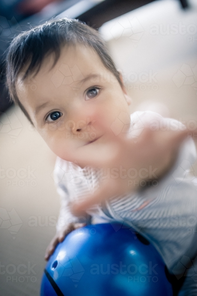 Cute 1 year old mixed race boy reaches out while playing at home - Australian Stock Image