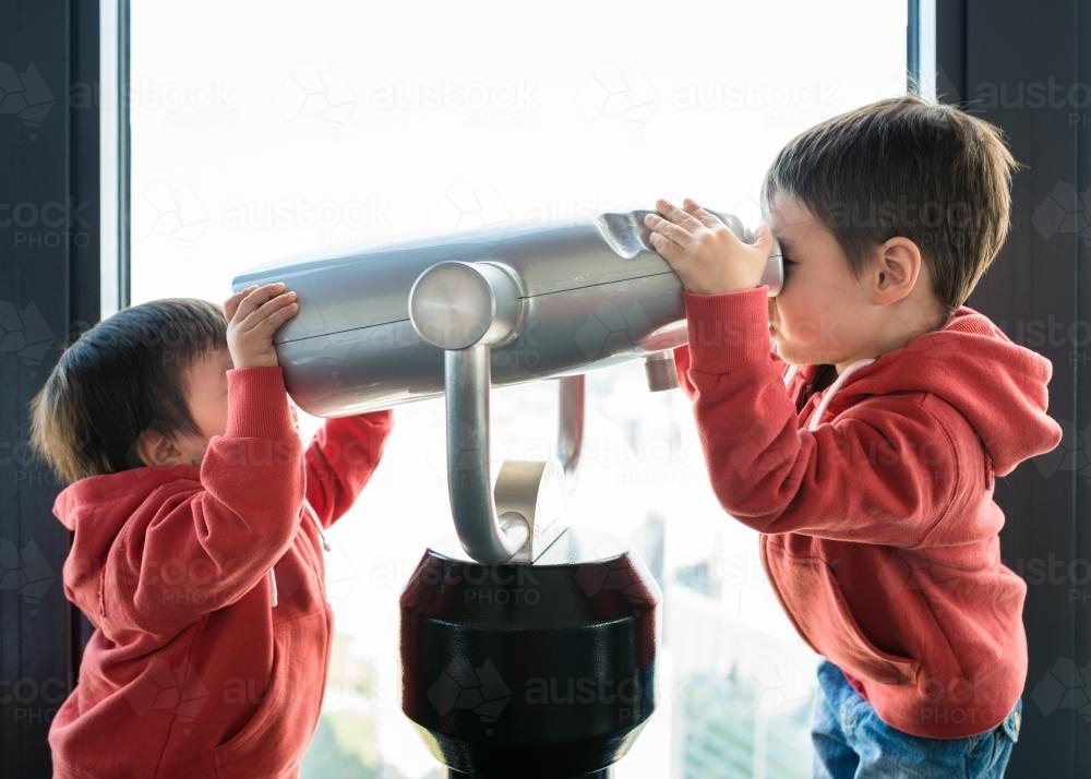 Cute 2 and 4 year old mixed race brothers play with binoculars in Sydney Centrepoint Tower - Australian Stock Image