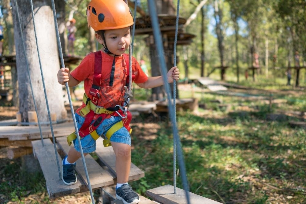 Cute 3 year old mixed race boy plays on an adventure ropes course - Australian Stock Image