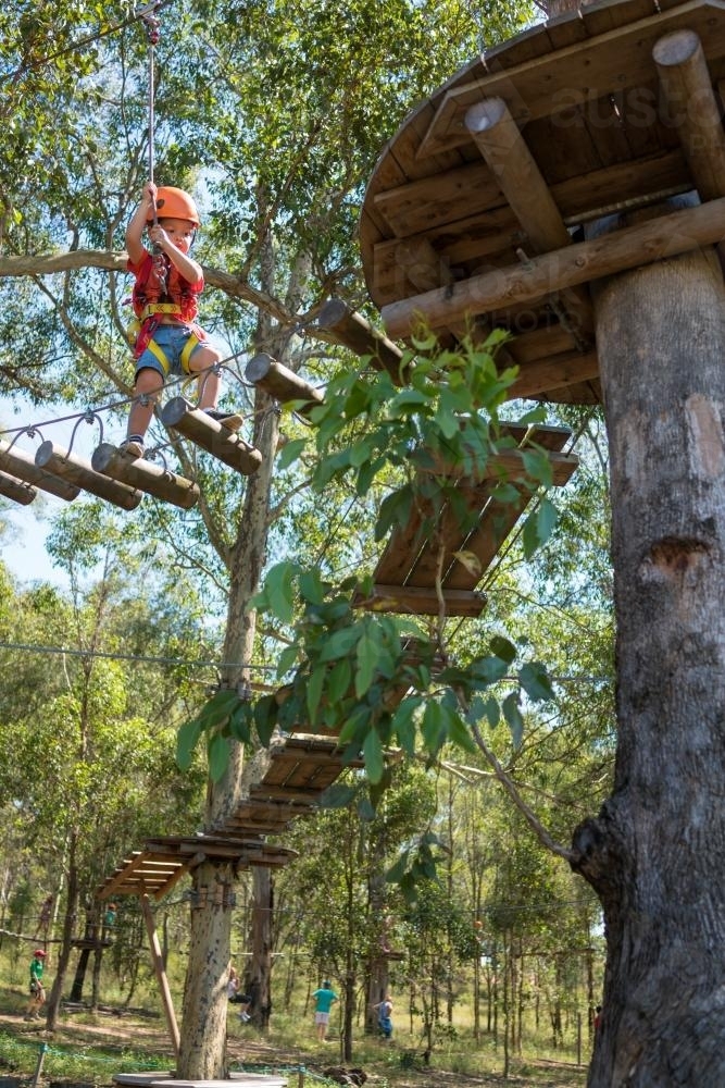 Cute 3 year old mixed race boy plays on an adventure ropes course - Australian Stock Image