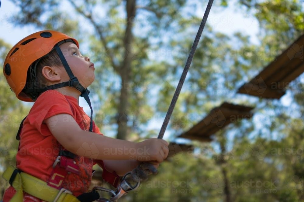 Cute 3 year old mixed race boy plays on an adventure ropes course - Australian Stock Image