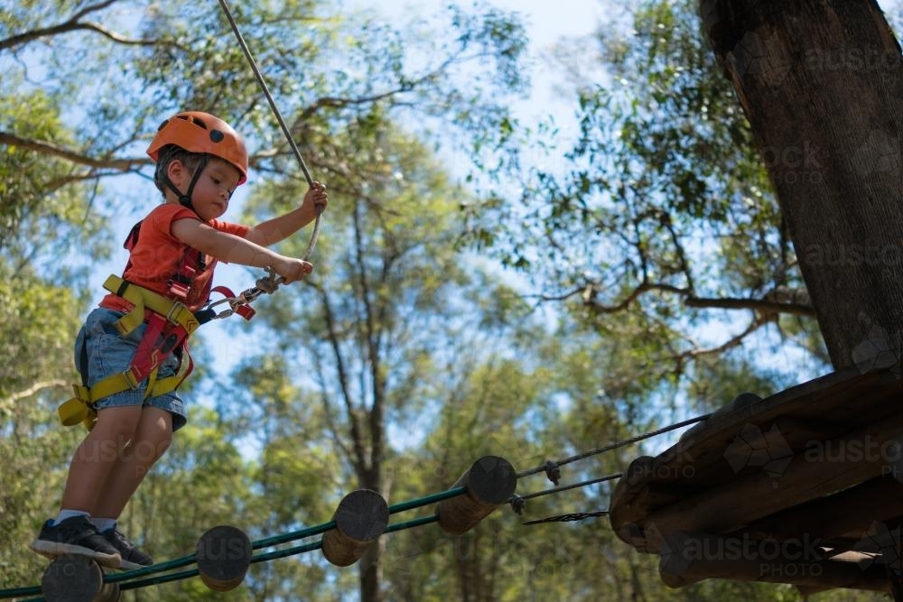Cute 3 year old mixed race boy plays on an adventure ropes course - Australian Stock Image