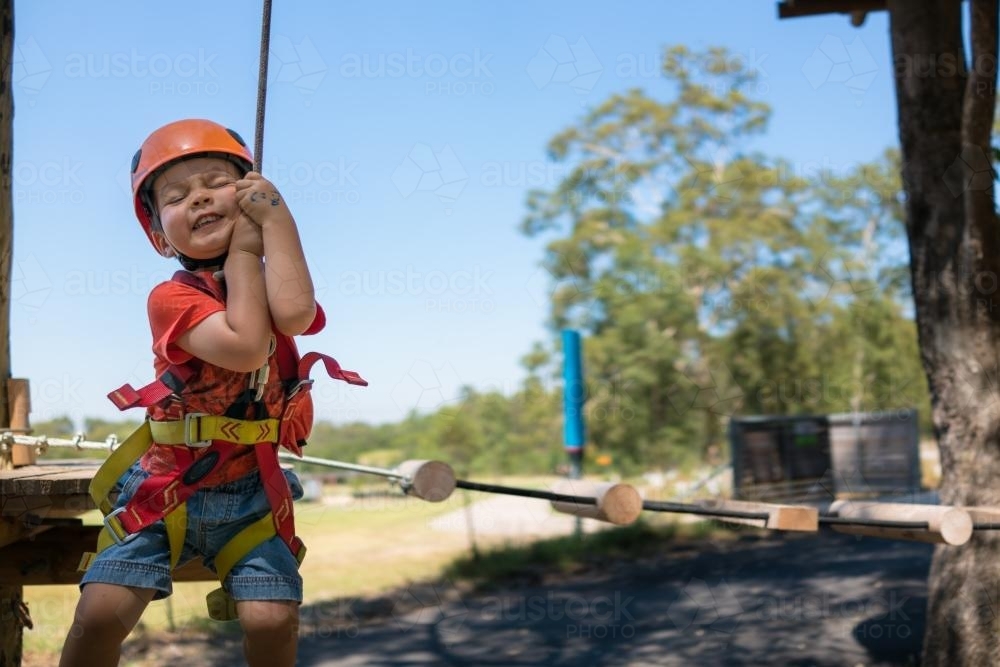 Cute 3 year old mixed race boy plays on an adventure ropes course - Australian Stock Image