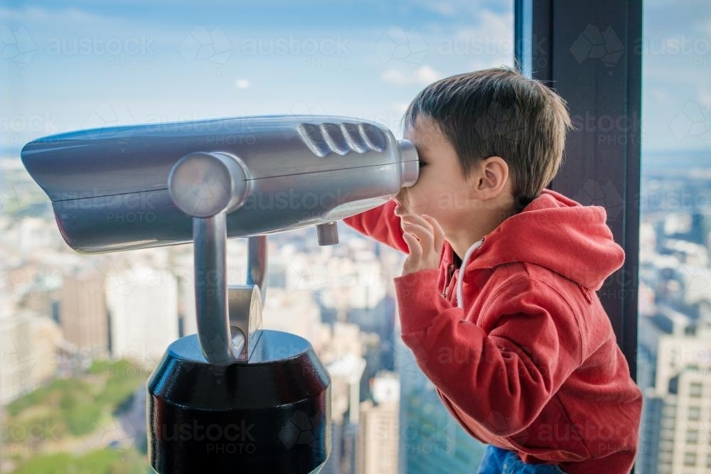 Cute 4 year old mixed race boy plays with a telescope in Sydney Centrepoint Tower - Australian Stock Image