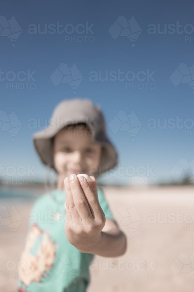 Cute 6 year old boy plays happily in the water and with shells on a Port Stephens beach - Australian Stock Image