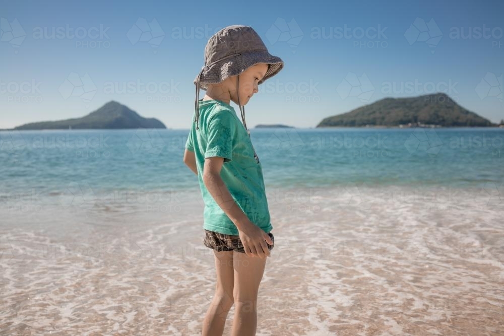 Cute 6 year old boy plays happily in the water on a Port Stephens beach - Australian Stock Image
