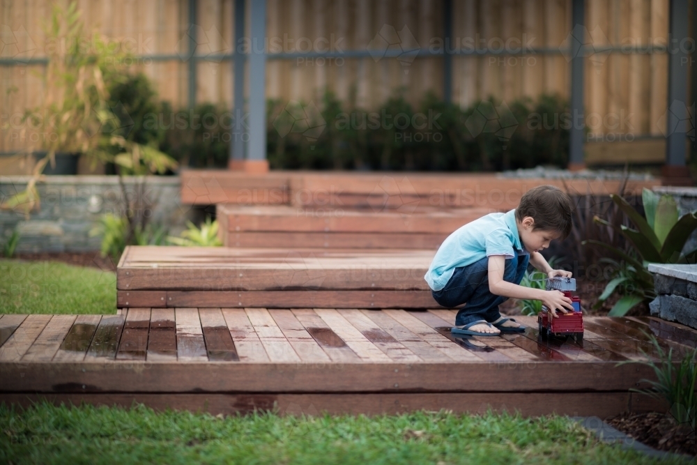 Cute 6 year old mixed race boy plays happily in his suburban backyard - Australian Stock Image