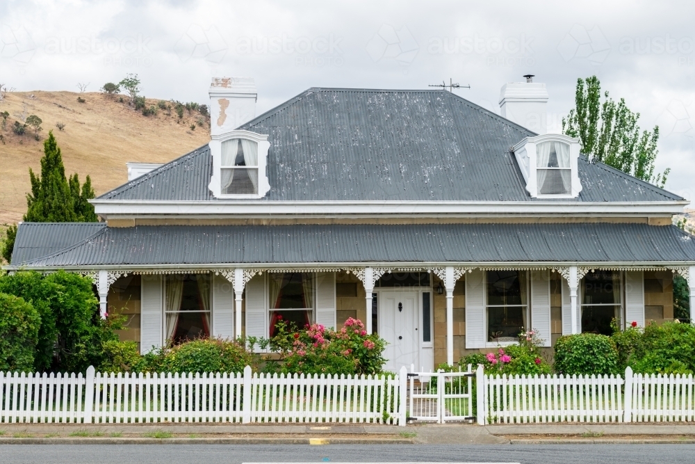 cute cottage with white fence, shutters and dormer windows - Australian Stock Image
