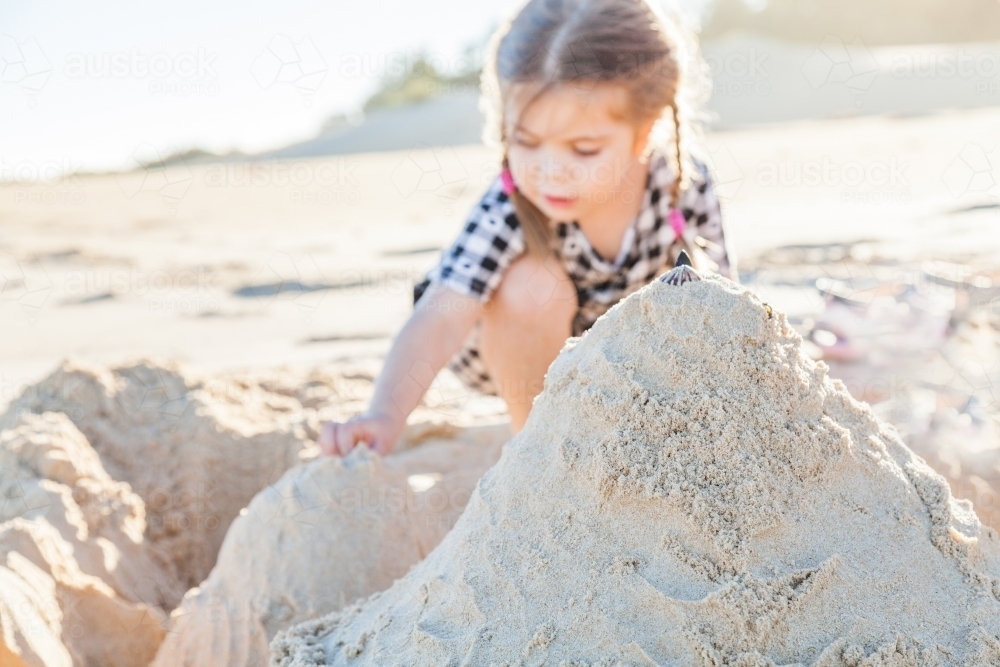 Cute happy little girl playing in sand in autumn sunlight - Australian Stock Image